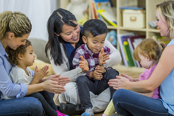 Three women seated each holding a small child in their laps